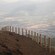 Un poste de madera y una valla de cuerdas en la cima de una montaña, desde la que se ve la civilización hacia abajo